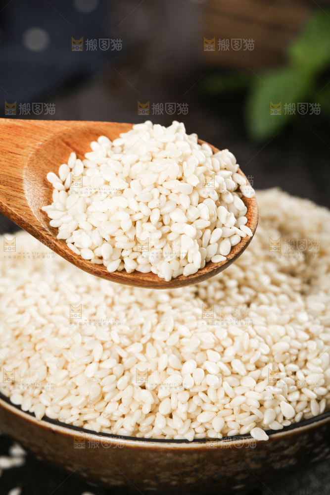 黑底上放着一碗东北芝麻和勺子上挖着芝麻
