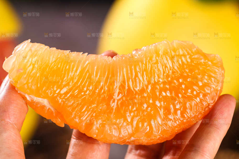 手上拿着一块黄心柚子果肉