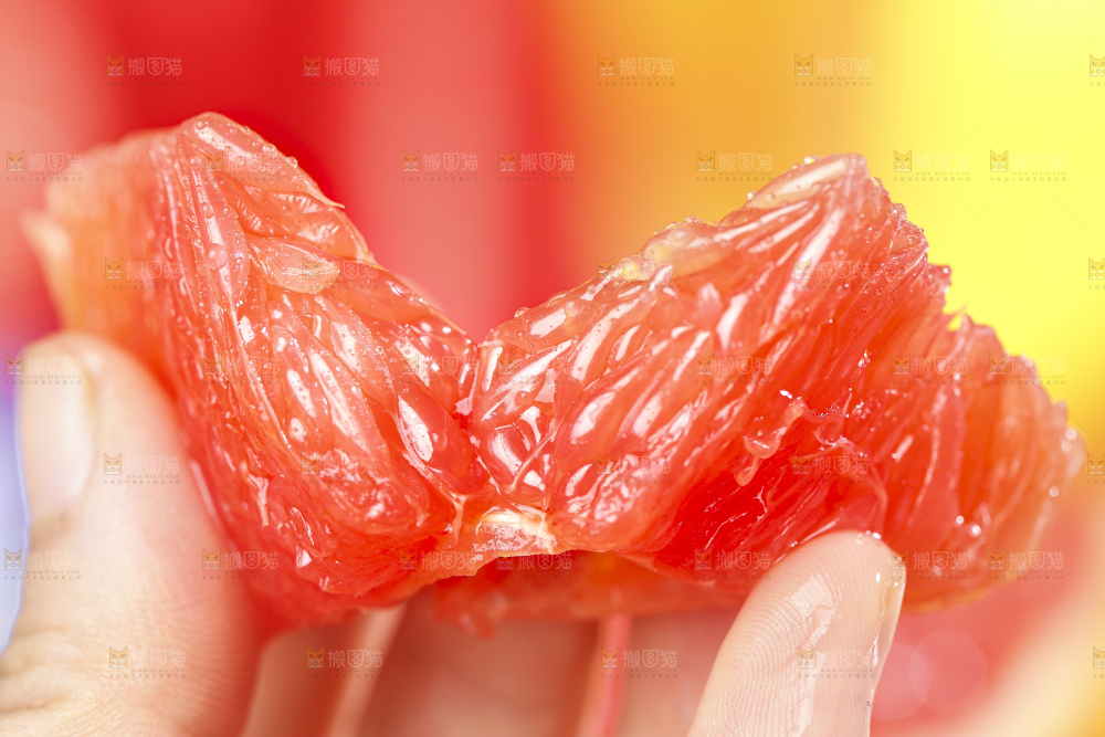 手拿着剥皮的红心葡萄柚果肉