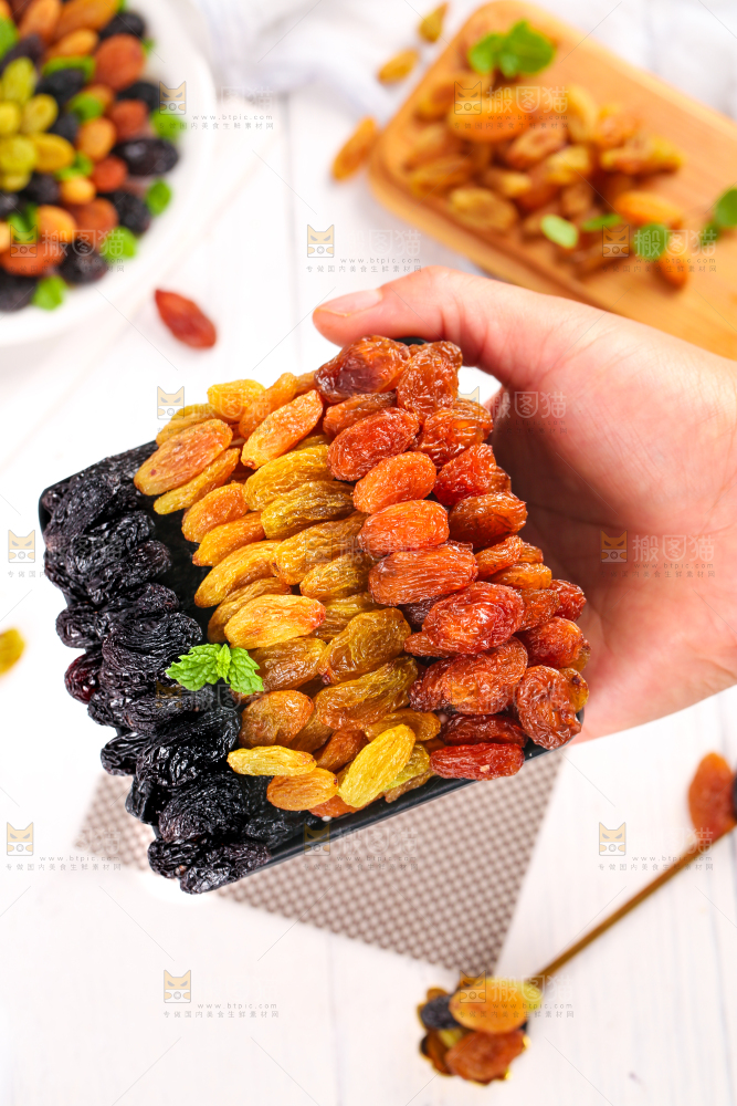 白木板上手拿一盘三色葡萄干