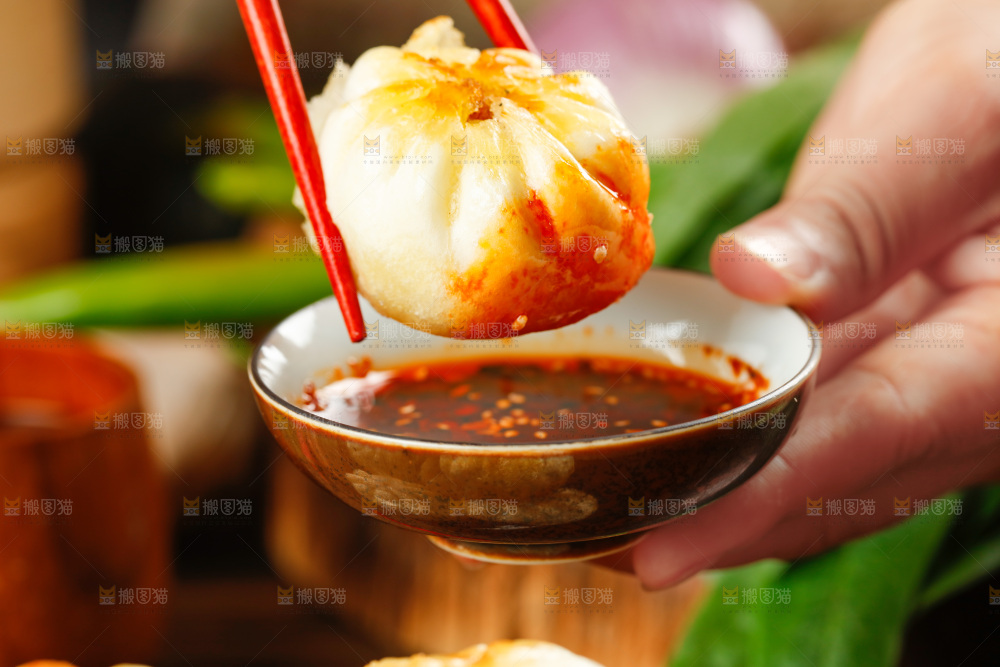筷子夹着蘸辣椒的煎包