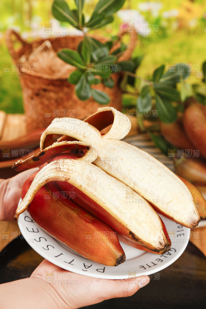 黑底上手捧一盘剥皮的红皮香蕉