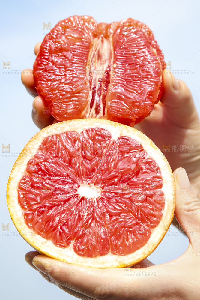 手拿着剥皮的红心葡萄柚果肉