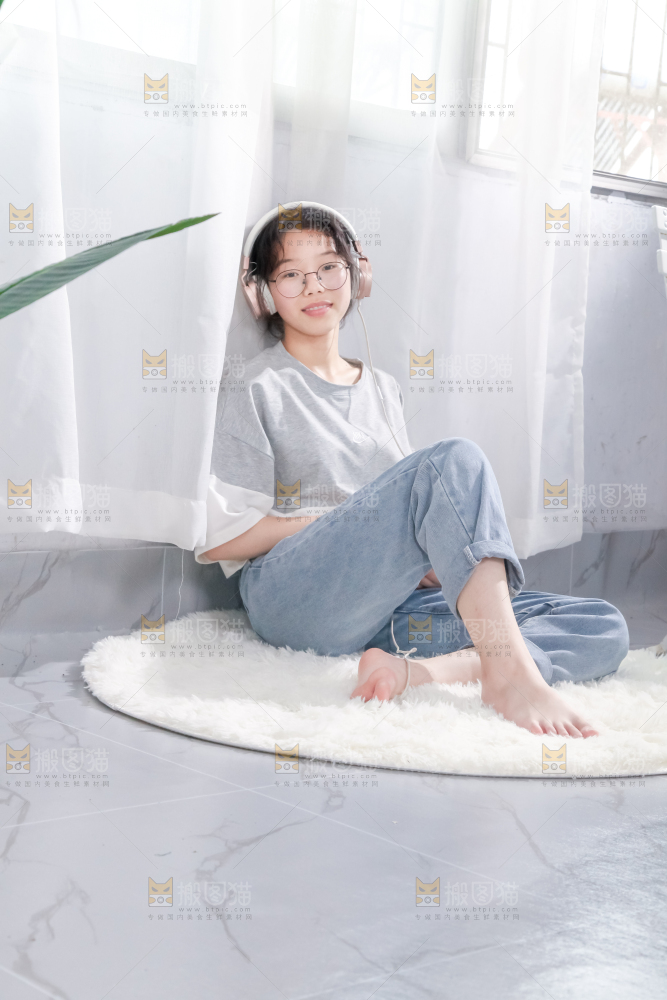 毛毯上坐着一位带耳机的女孩