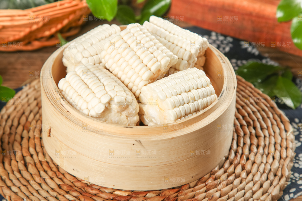 编织垫上摆放着水果白玉米