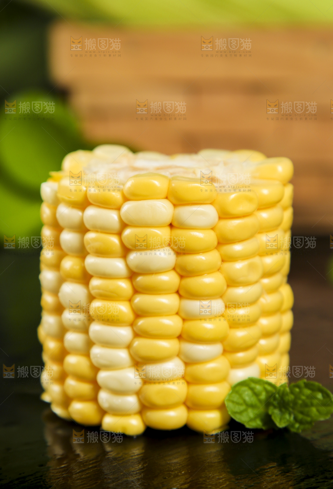黑石板上放着掰开的甜玉米