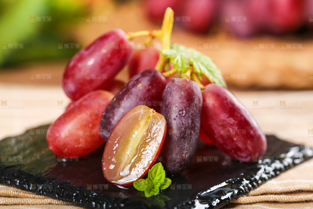 黑石板上放着切开的澳洲美人指葡萄