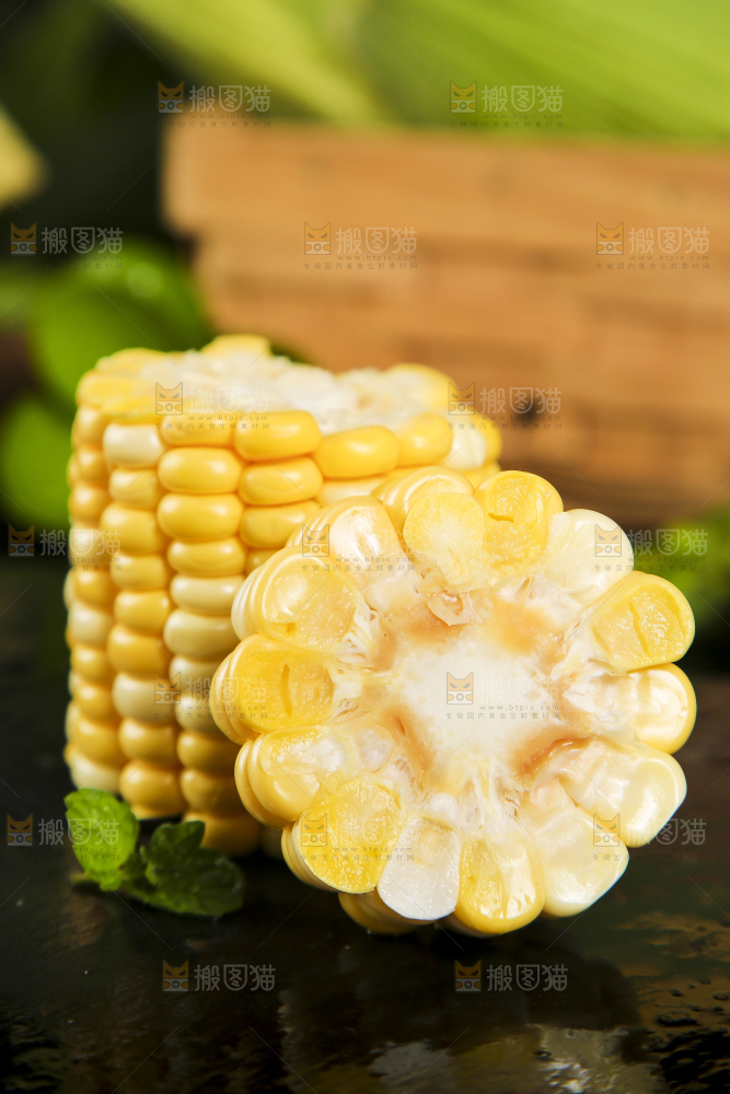 黑石板上放着掰开的甜玉米