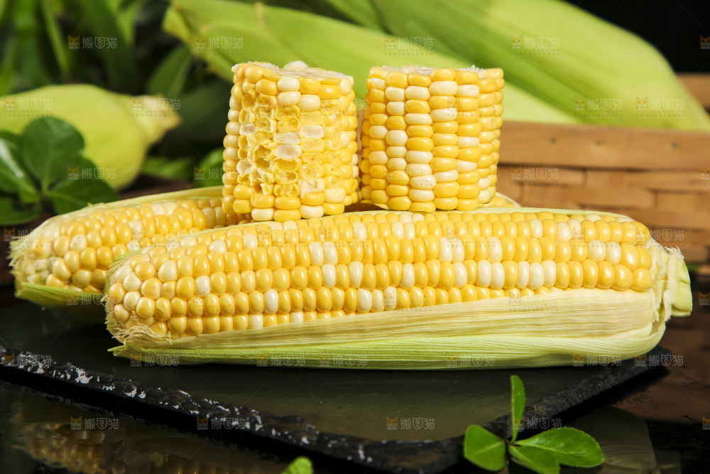 黑石板上放着剥皮的甜玉米
