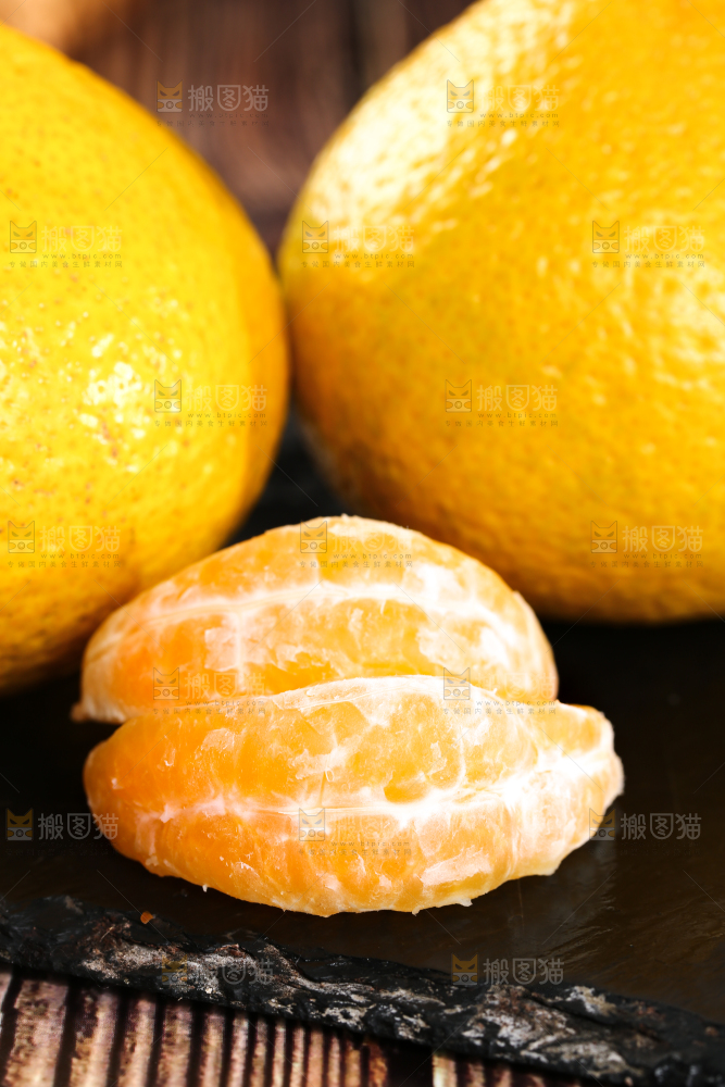 黑底上摆放着桔柚和桔柚果肉