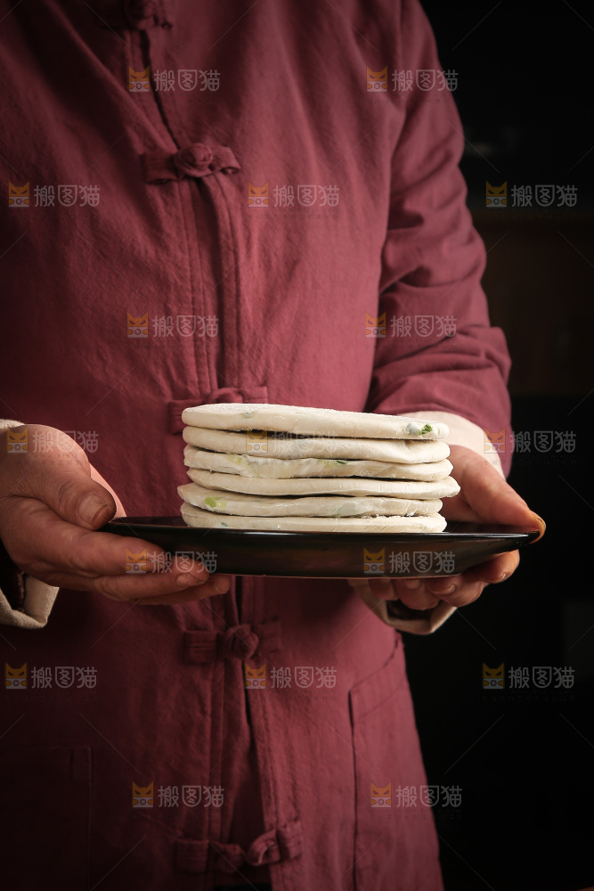 手里端着一盘葱油饼