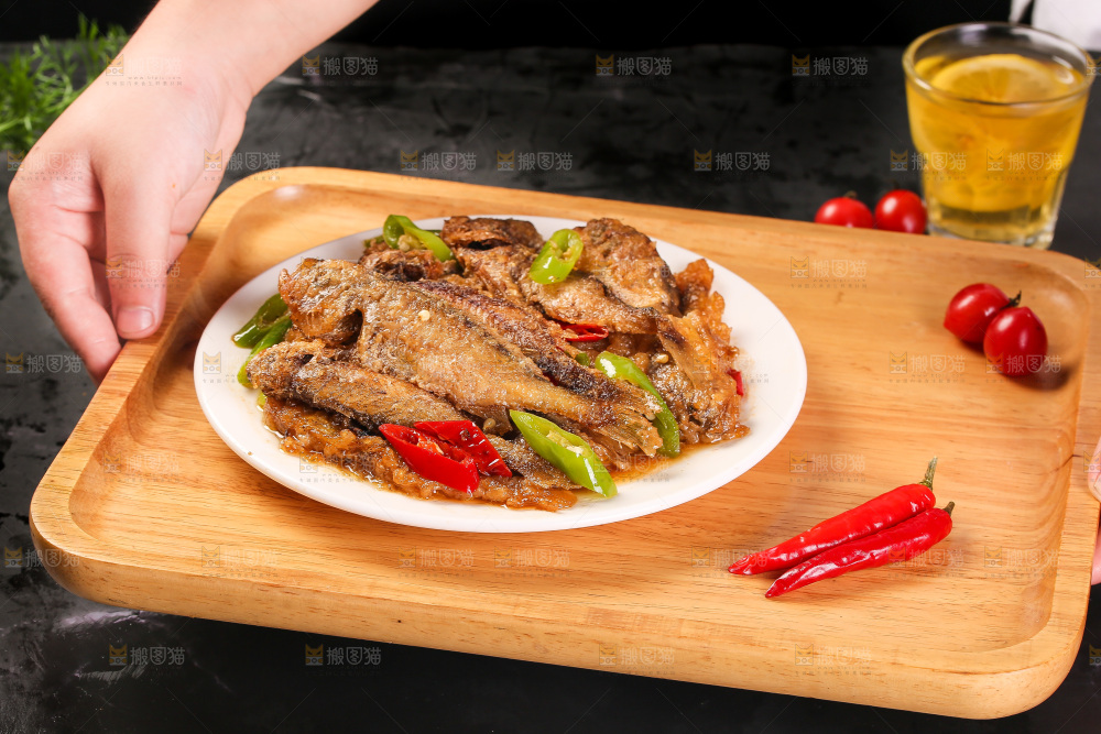 手端着一盘香酥煎鱼