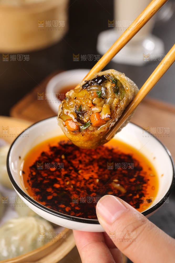 筷子上夹着蘸酱的包子