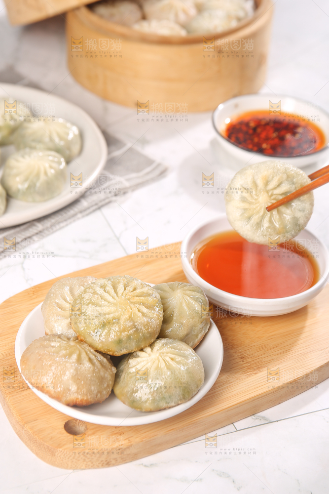 筷子夹着蘸料的小包子