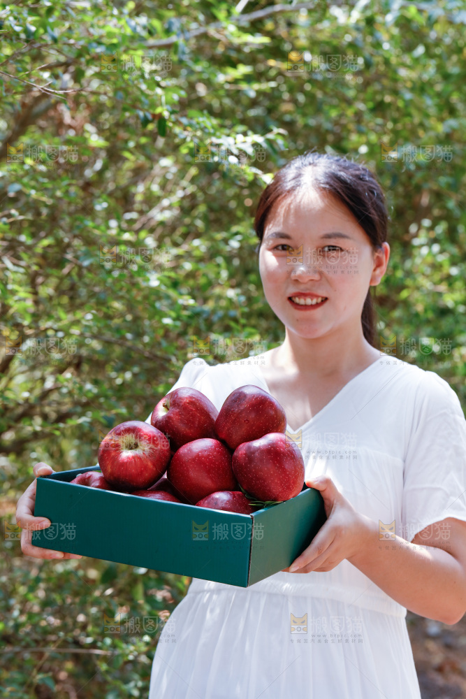 女孩手里拿着一盒花牛苹果