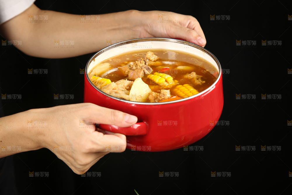 手里端着一碗玉米胡萝卜排骨汤