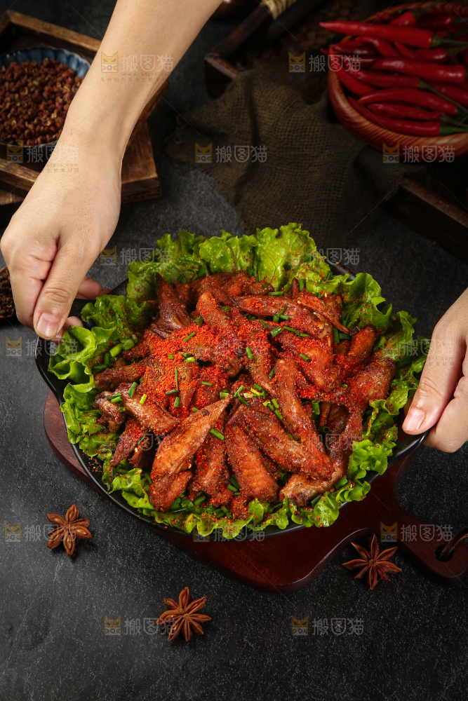 手里端着一盘香辣孜然鸡翅尖