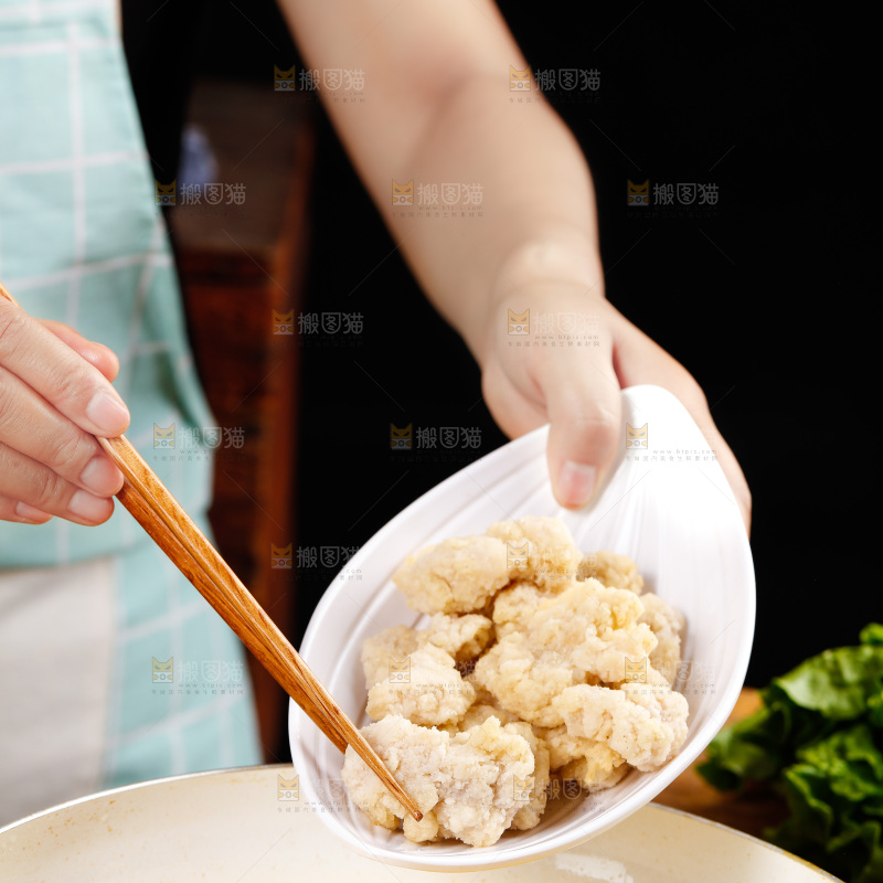 手上端着一盘盐酥鸡和筷子上夹着鸡块