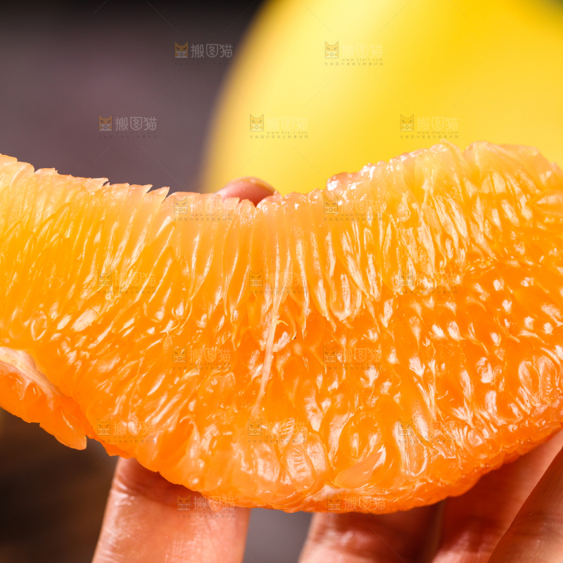 手上拿着一块黄心柚子果肉