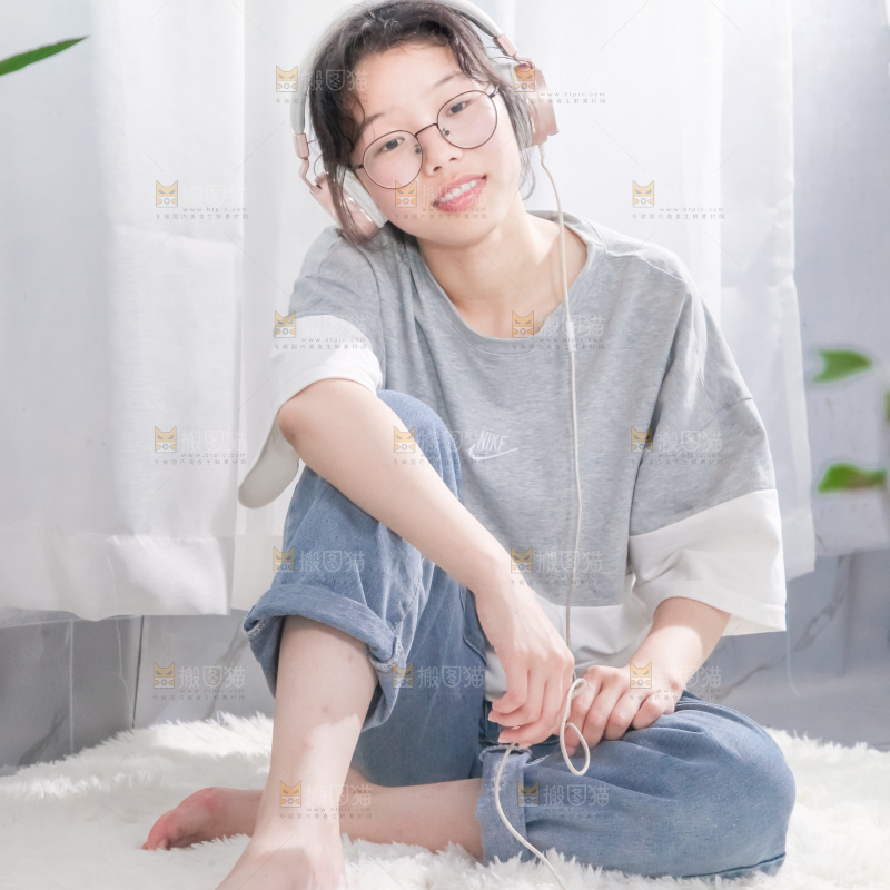 毛毯上坐着一位带耳机的女孩