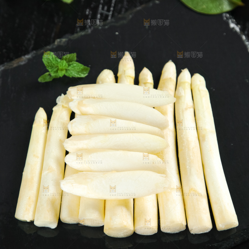 黑石板上放着切开的白芦笋