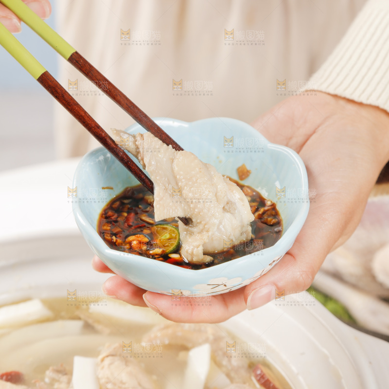 筷子上夹着蘸汁的椰子鸡